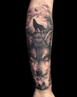 Avi's striking black and gray forearm tattoo featuring a powerful wolf surrounded by elegant birds.