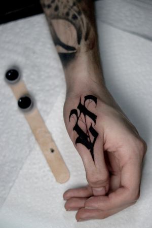 Unique blackwork design combining lettering and illustrative motifs by Alejandro Gonzalez. Perfect for a small but eye-catching tattoo on your finger.