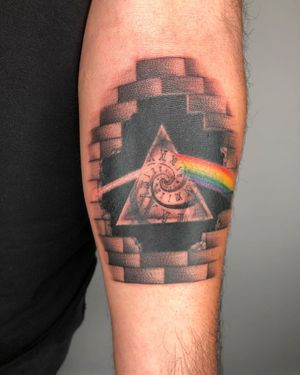 Illustrative black and gray tattoo on forearm by Drone, featuring a rainbow intertwined with a clock and watch design.