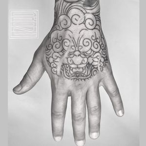 Get a fierce and striking foo dog tattoo on your hand by Drone, blending traditional Japanese style with modern blackwork.