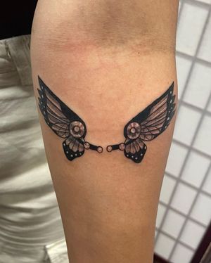 Elegant black and gray butterfly wings tattoo on lower leg by Michaelle Fiore, combining realism and illustration.