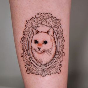 An illustrative tattoo by Erin featuring a cat, flower, filigree, and frame on the arm.
