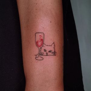 Illustrative upper arm tattoo by Erin featuring a cat in a glass with wine design