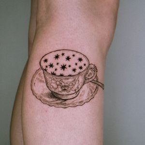 Blackwork star, cup, tea, house, and spoon illustration on lower leg by Erin. A whimsical design for tea lovers.