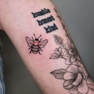 Get a stunning fine line illustrative tattoo of a bee and heart design on your arm by the talented artist Erin.