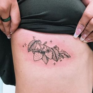 Beautiful blackwork tattoo featuring a flower and strawberry design on the ribs, by talented artist Erin.