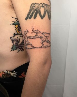 Unique upper arm tattoo featuring a fine line design of a fencing rat by Ermis Atzemoglou. Perfect for animal and sports enthusiasts!