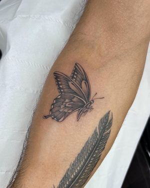 A stunning black and gray fine line butterfly tattoo on the lower leg by Sophie Rose Hunter.
