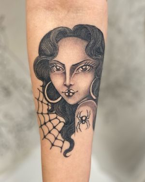 Sophie Rose Hunter's black and gray forearm tattoo combines a spider and woman motifs in a chicano style design.