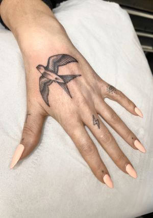 Capture the beauty of nature with this black and gray swallow bird tattoo on your hand by artist Sophie Rose Hunter.