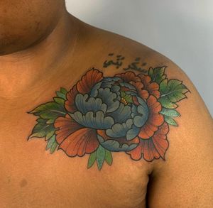 Elegant and intricate chest tattoo featuring a beautiful peony flower, expertly done by Karen Buckley.
