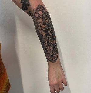 Experience Karen Buckley's intricate dotwork and geometric design featuring a stunning flower motif on your lower arm.