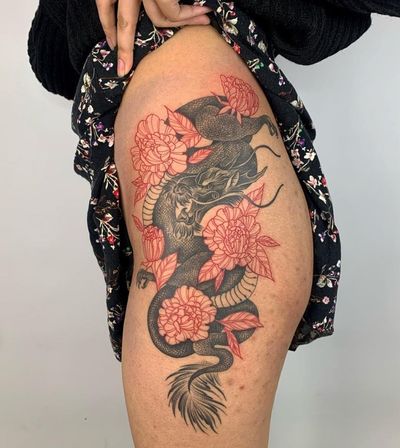 Stunning upper leg tattoo by artist Karen Buckley featuring a fierce dragon intertwined with a delicate peony flower in traditional Japanese style.