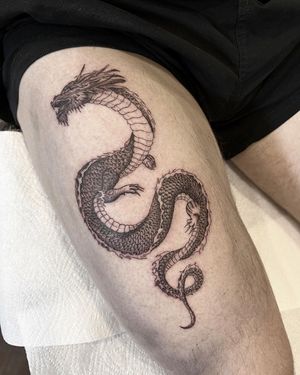 Discover a stunning black and gray dragon tattoo on the upper leg, expertly done by Federico Colantoni. Fine lines bring this mythical creature to life.