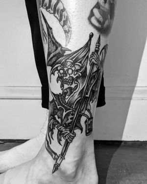 Get an edgy lower leg tattoo by Shane featuring a skull with wings in bold blackwork style.