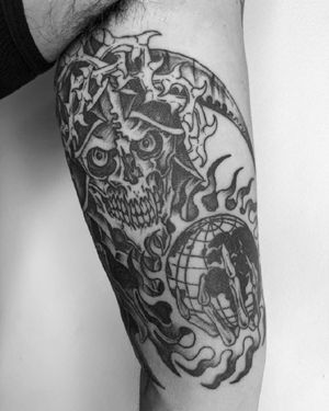 A striking blackwork tattoo on the upper arm featuring a skull, world, and thorns, expertly done by Shane in an illustrative style.