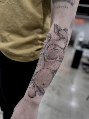 A stunning black and gray tattoo of luscious fruit on the forearm, beautifully rendered by Lawrence.