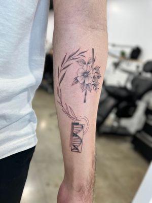 Lawrence's illustrative blackwork tattoo combines elements of science and nature with a unique twist of floral and DNA motifs on the forearm.