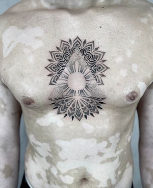 Experience the mesmerizing beauty of blackwork and dotwork in this mandala chest tattoo by the talented artist Lawrence.