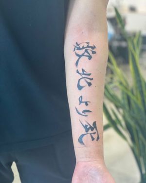 Blackwork forearm tattoo featuring a meaningful kanji quote elegantly done by tattoo artist Kotaro.