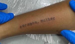 Tatuagem “coragem,mulher” com fonte de máquina de escrever.