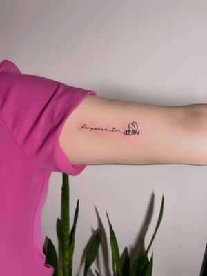 Delicate fine line tattoo with small lettering by Cha, exuding a sense of peace and calmness.