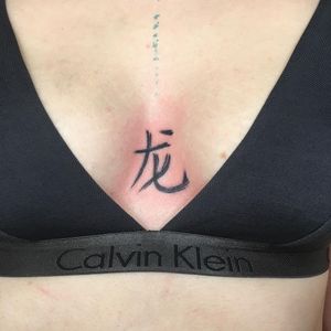 Elegant blackwork chest tattoo featuring kanji, a meaningful quote, and beautiful brush strokes. A true work of art!
