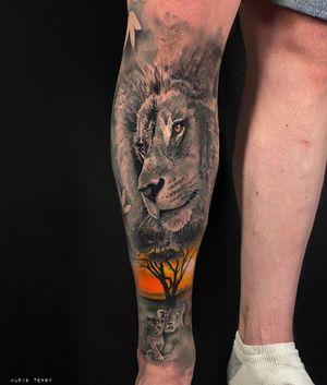 This stunning black and gray tattoo by Marie Terry features a lifelike lion and tree motif, beautifully executed on the lower leg.