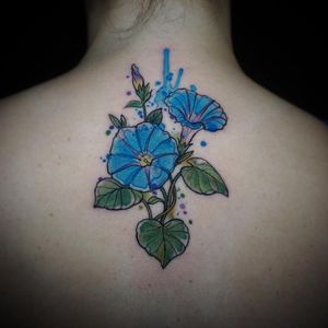 Beautiful watercolor flower motif tattoo on the upper back by Aygul, showcasing vibrant colors and delicate petals.