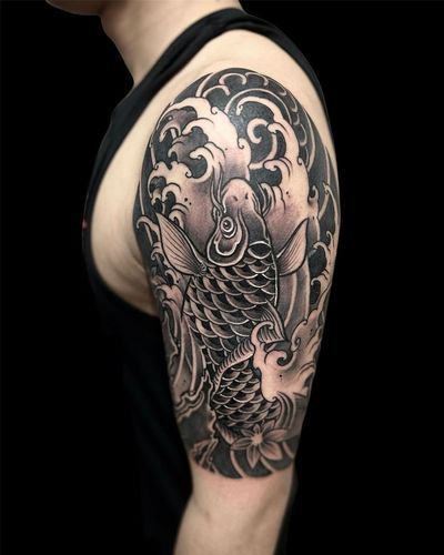 Get an illustrative Japanese tattoo on your upper arm featuring sea motifs like fish and waves by talented artist Avi.