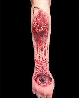 Experience the surrealism of death with Avi's realistic and illustrative forearm tattoo featuring a grim reaper, scythe, and eye motif.
