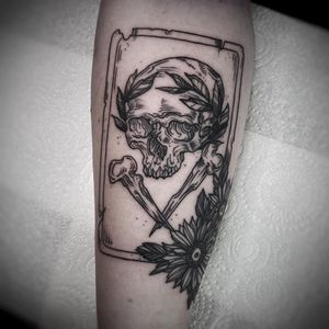 Get a bold and detailed black and gray traditional tattoo of a skull and bones on your forearm by the talented artist Lamat.