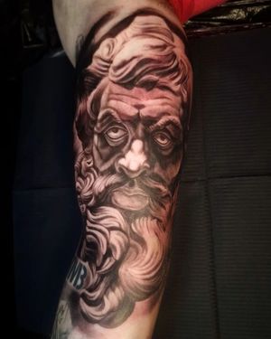 Capture the timeless elegance of a statue in black and gray on your upper arm by Mauro Imperatori.