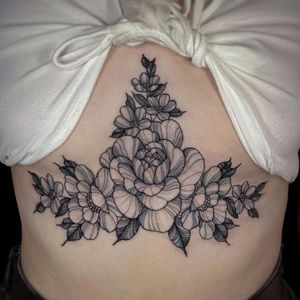 Intricate design of flowers and leaves by tattoo artist Lamat, adding a touch of elegance and femininity to the underboob area.
