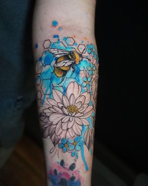 Beautifully crafted bee and flower design by Aygul, blending geometric lines and watercolor shades for a unique and artistic forearm tattoo.