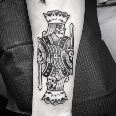 Impressive black and gray tattoo featuring a sword, king, and card motif on the forearm, expertly done by the talented artist Matthew Ono.