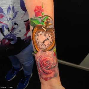 Marie Terry combines delicate small lettering with realistic flower and clock motifs for a stunning forearm tattoo.