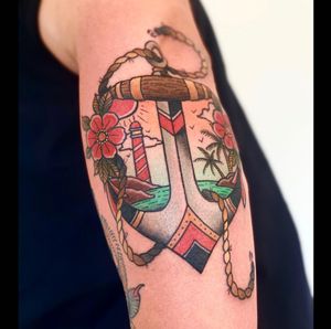 Get a classic traditional tattoo featuring a beautiful flower and anchor design on your upper arm by the talented artist, Lamat.