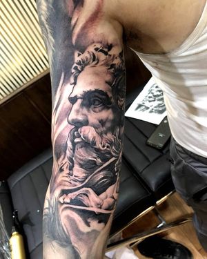 Get a striking blackwork tattoo of Poseidon on your upper arm by talented artist Avi. Make a powerful statement with this mythological piece.