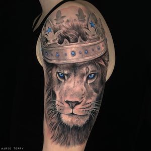 Impressive black and gray realism lion wearing a majestic crown, expertly done by tattoo artist Marie Terry on the upper arm.