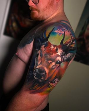 Capture the beauty of winter with this stunning and detailed upper arm tattoo of a deer in a snowy forest, by Cloto.tattoos.
