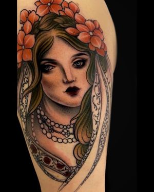 Featuring a stunning fusion of delicate flowers and a beautiful woman, this upper arm tattoo by Edyta embodies the neo-traditional style.