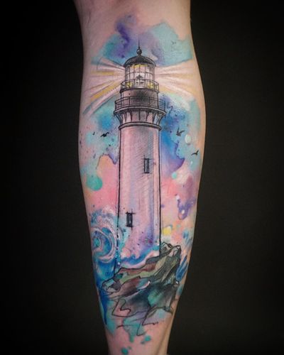 Capture the beauty of the sea with this stunning watercolor lighthouse tattoo by Aygul. The sketchwork adds a unique touch to this piece.