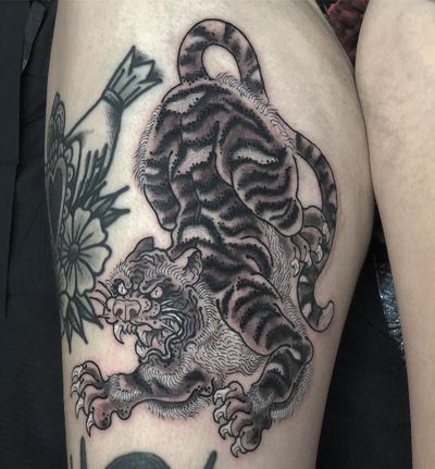 Experience the power and beauty of a Japanese tiger with striking black and gray stripes, expertly inked by Matthew Ono on your upper leg.
