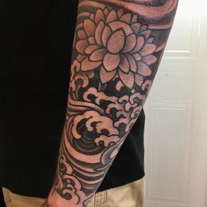 Exquisite blackwork illustration of lotus flower and waves by Kiko Lopes, perfect for forearm placement.