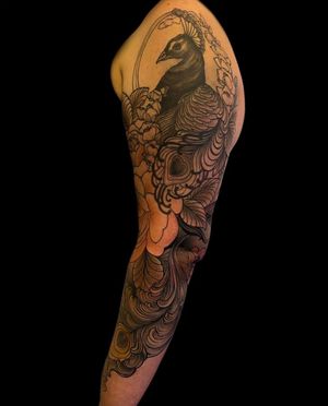 Intricate black & gray peacock design with vibrant flowers, expertly crafted in neo-traditional style by artist Edyta.
