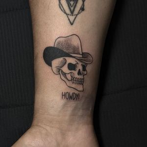 Get a small lettering forearm tattoo featuring a unique skull cowboy design by artist Luca Salzano. Show off your rugged side with this edgy ink!