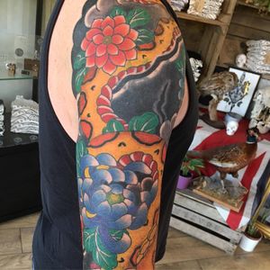 Intricate illustrative design by Kiko Lopes featuring a stunning combination of a snake and flower motif on the upper arm.