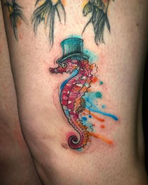 Beautiful seahorse tattoo by Aygul blending fine line and watercolor styles on upper leg.