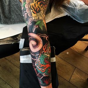 Experience the power and beauty of Japanese art with this sleeve tattoo featuring a fierce tiger and mystical dragon, expertly crafted by tattoo artist Kiko Lopes.